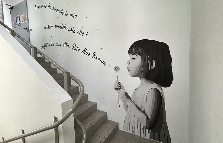 foto dell'opera di Goran castellotti dentro la biblioteca di colturano raffigurante una bambina che soffia un soffione da cui escono delle parole