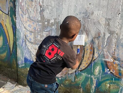 bambino che pittura un muro durante un laboratorio creativo di Goran castellotti