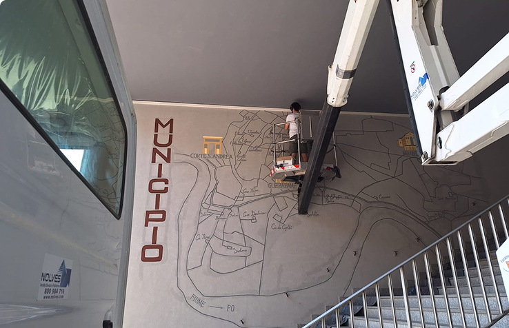 Goran castellotti su un cestello elevatore mentre realizza un'opera all'ingresso del comune di Senna Lodigiana